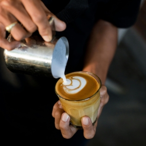 Close-up of a barista creating intricate latte art with milk in a coffee cup. Perfect for coffee enthusiasts.